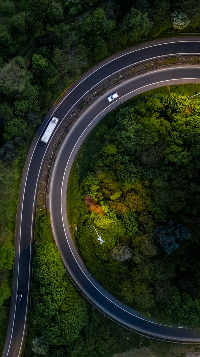 Stunning aerial view of a curved road surrounded by lush greenery in Leeds, United Kingdom.